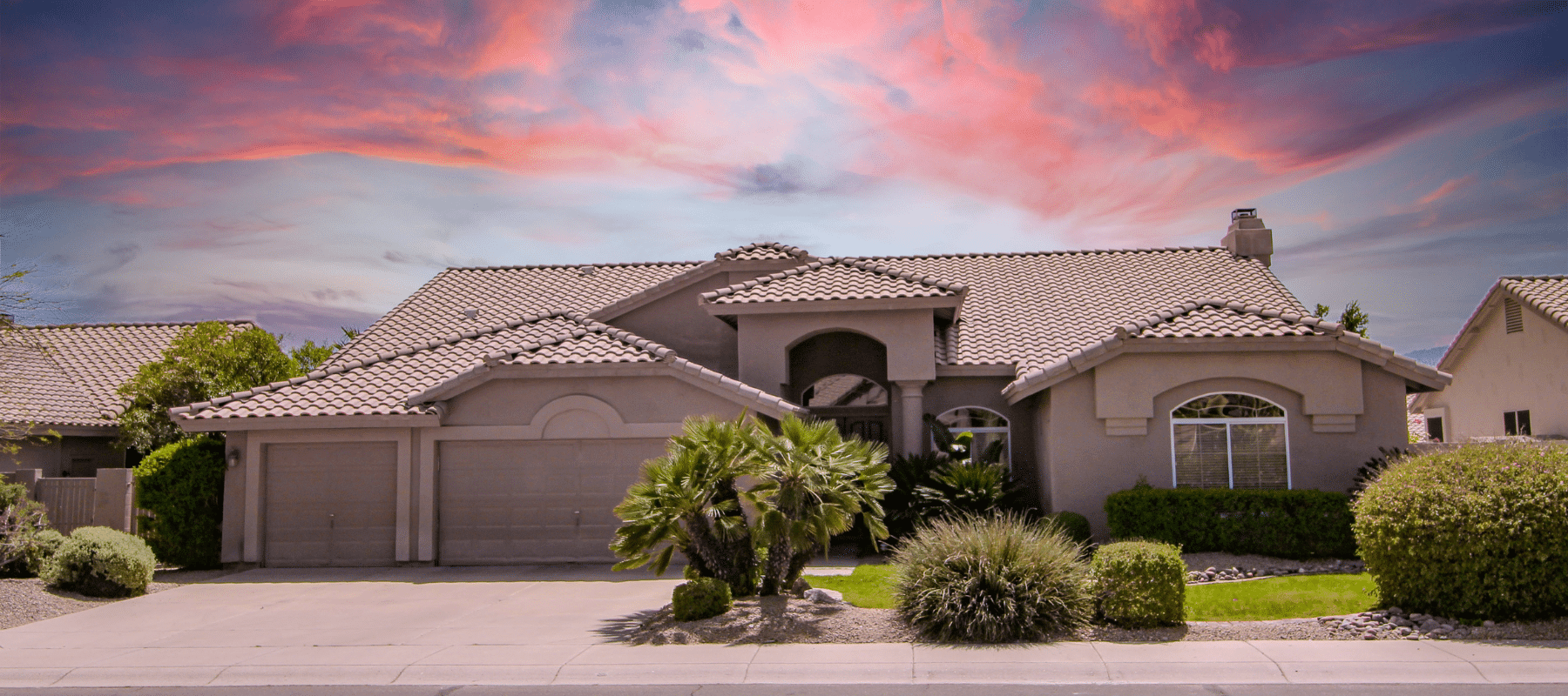 Elegant suburban house with a tile roof, framed by a vibrant sunset sky