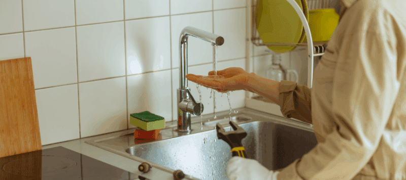 Person checking water flow at sink
