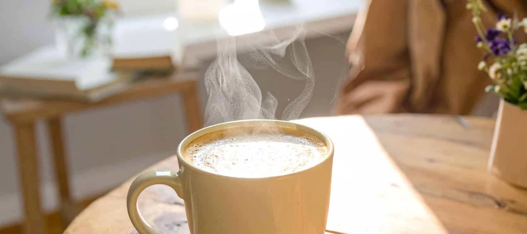 Steaming cup of coffee on table