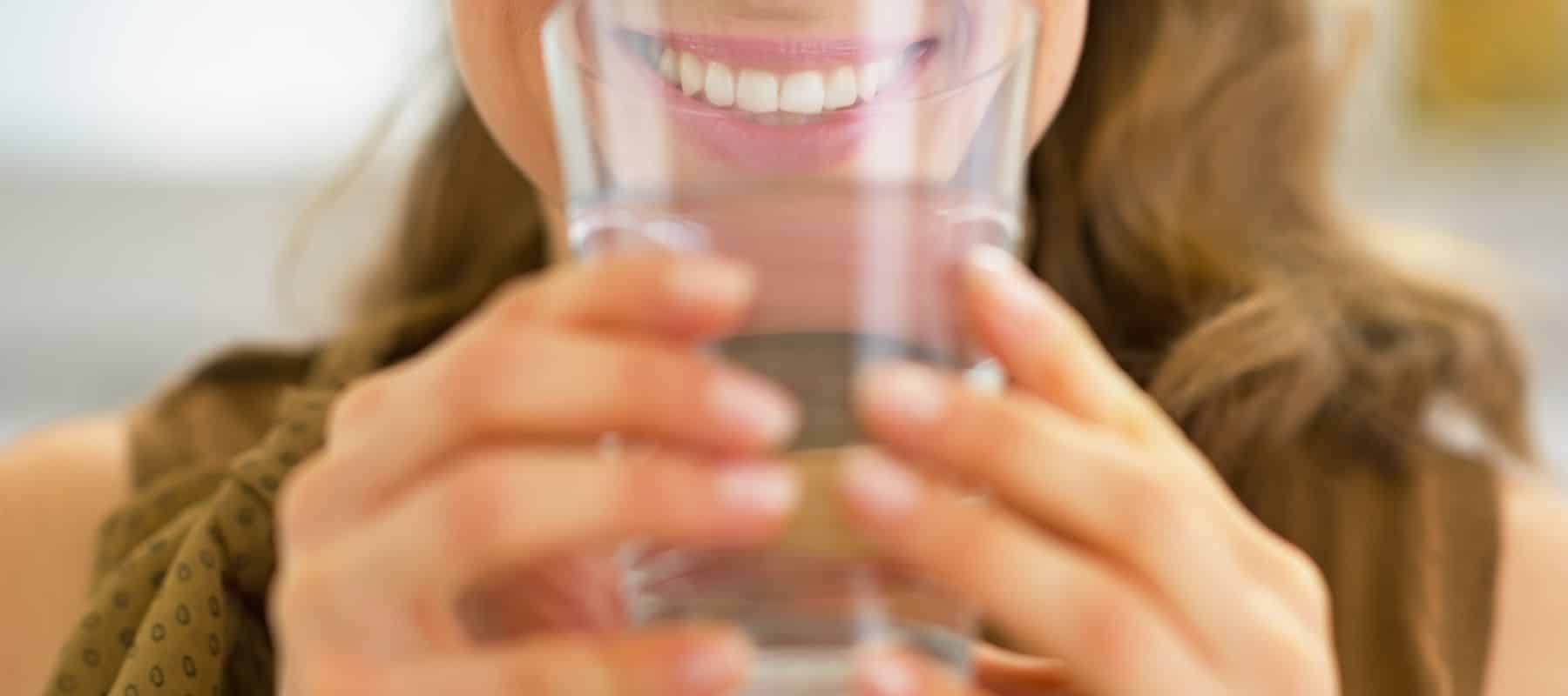 Smiling person holding a glass of water.